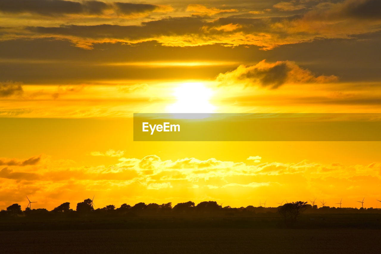 SILHOUETTE LANDSCAPE AGAINST BRIGHT SUN DURING SUNSET