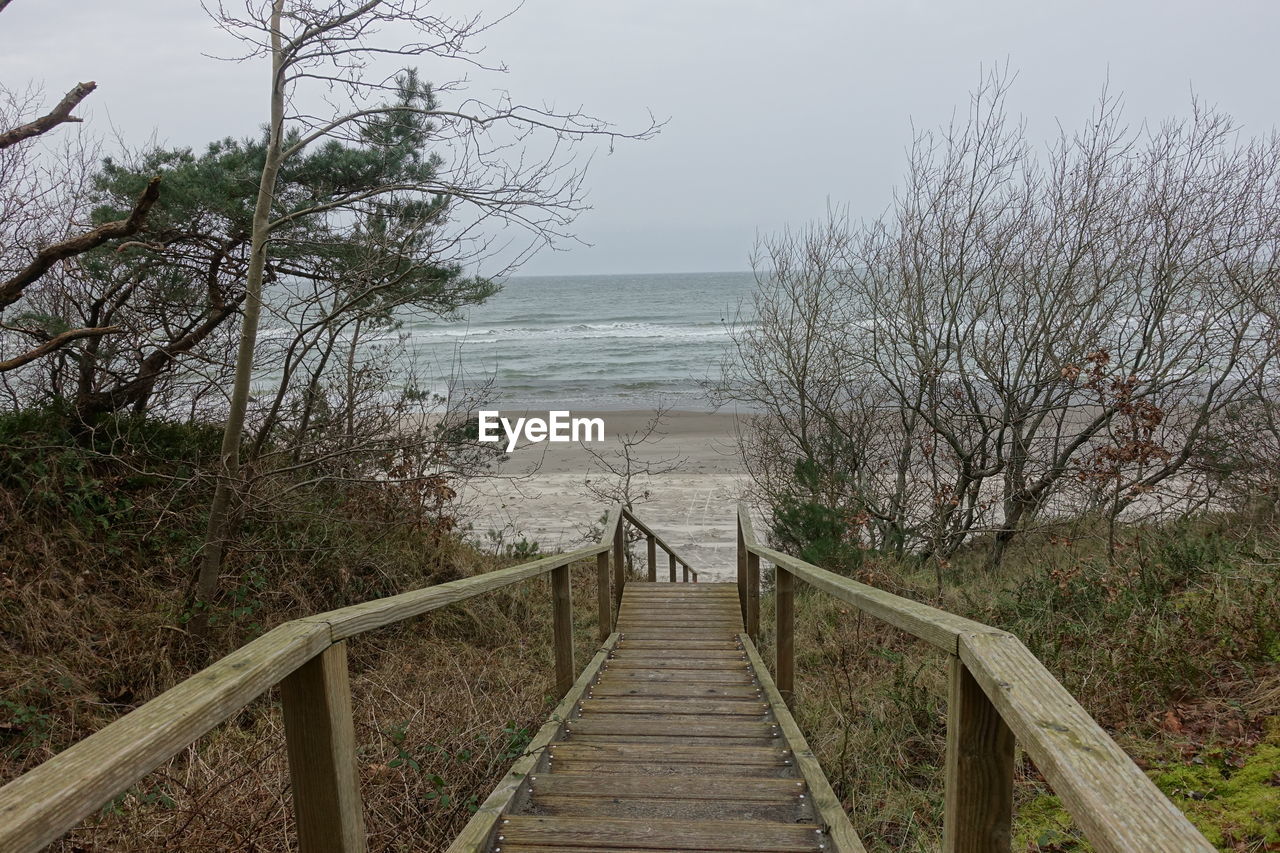 WOODEN FOOTBRIDGE OVER SEA AGAINST CLEAR SKY