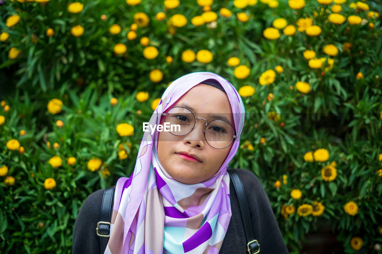 Portrait of smiling woman against flowering plants