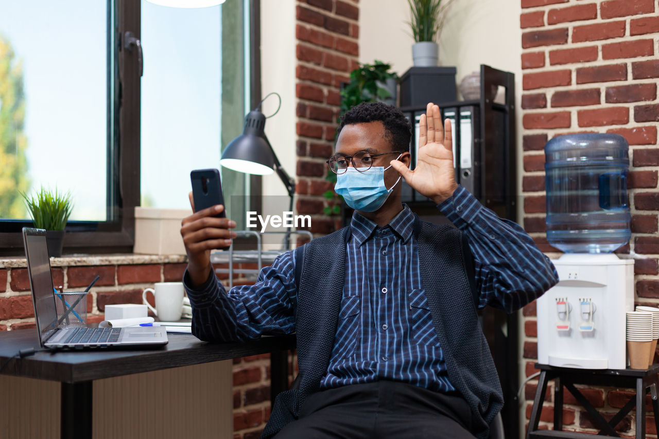 Businessman wearing mask talking on video call at office