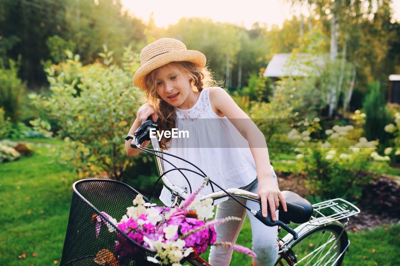 Smiling girl riding bicycle against trees