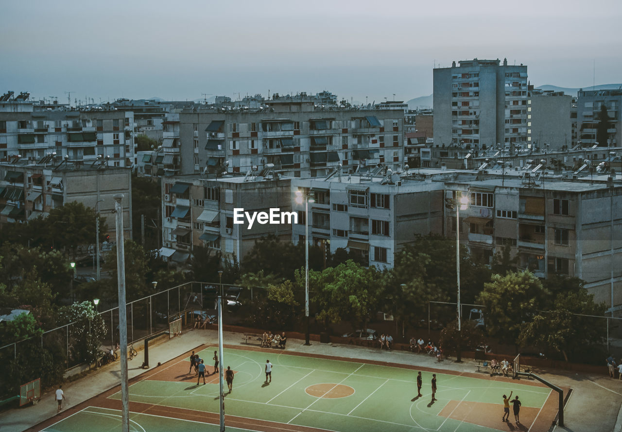 High angle view of people playing soccer on field against buildings