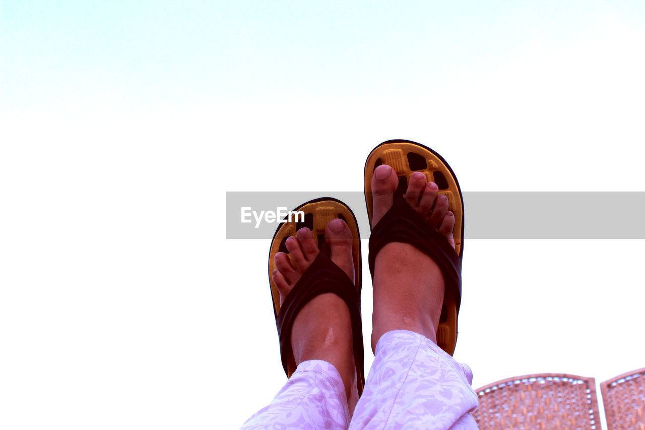 Low section of person with feet up against sky