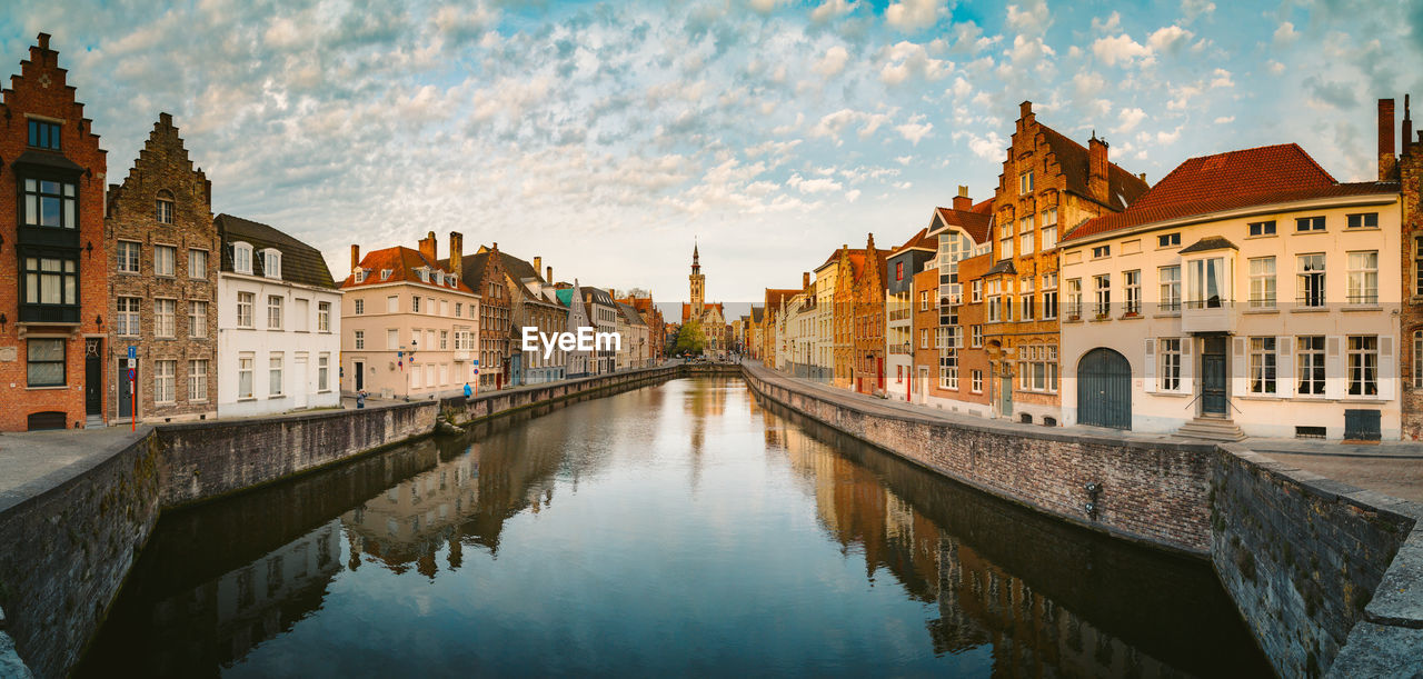 Panoramic view of canal amidst buildings in city during sunset