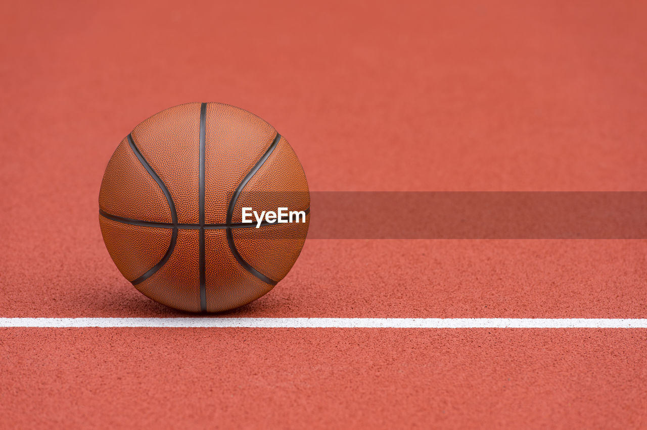 CLOSE-UP OF BASKETBALL HOOP AGAINST RED ORANGE WALL