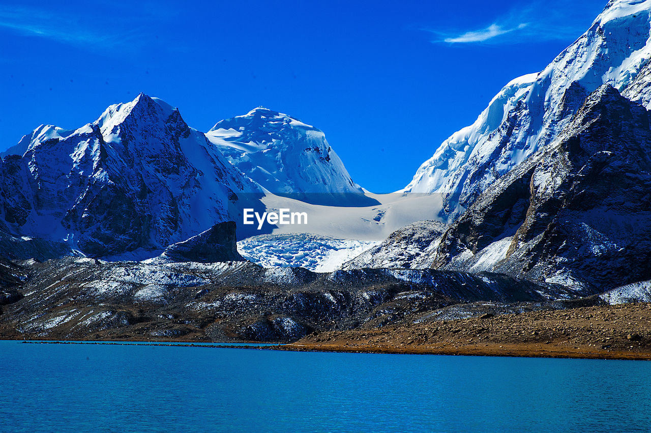 SNOWCAPPED MOUNTAINS AGAINST BLUE SKY DURING WINTER