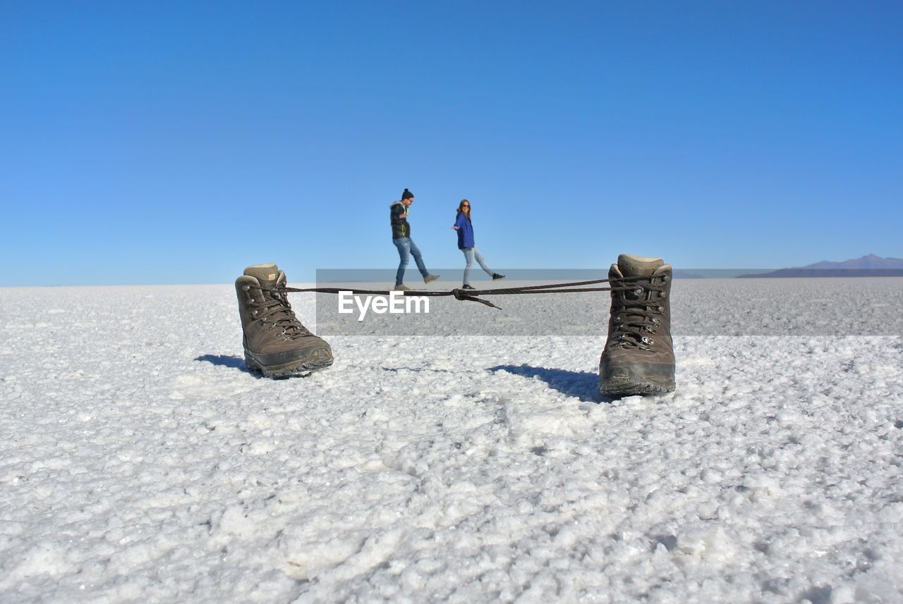 Optical illusion of couple walking on shoelaces at salt flat