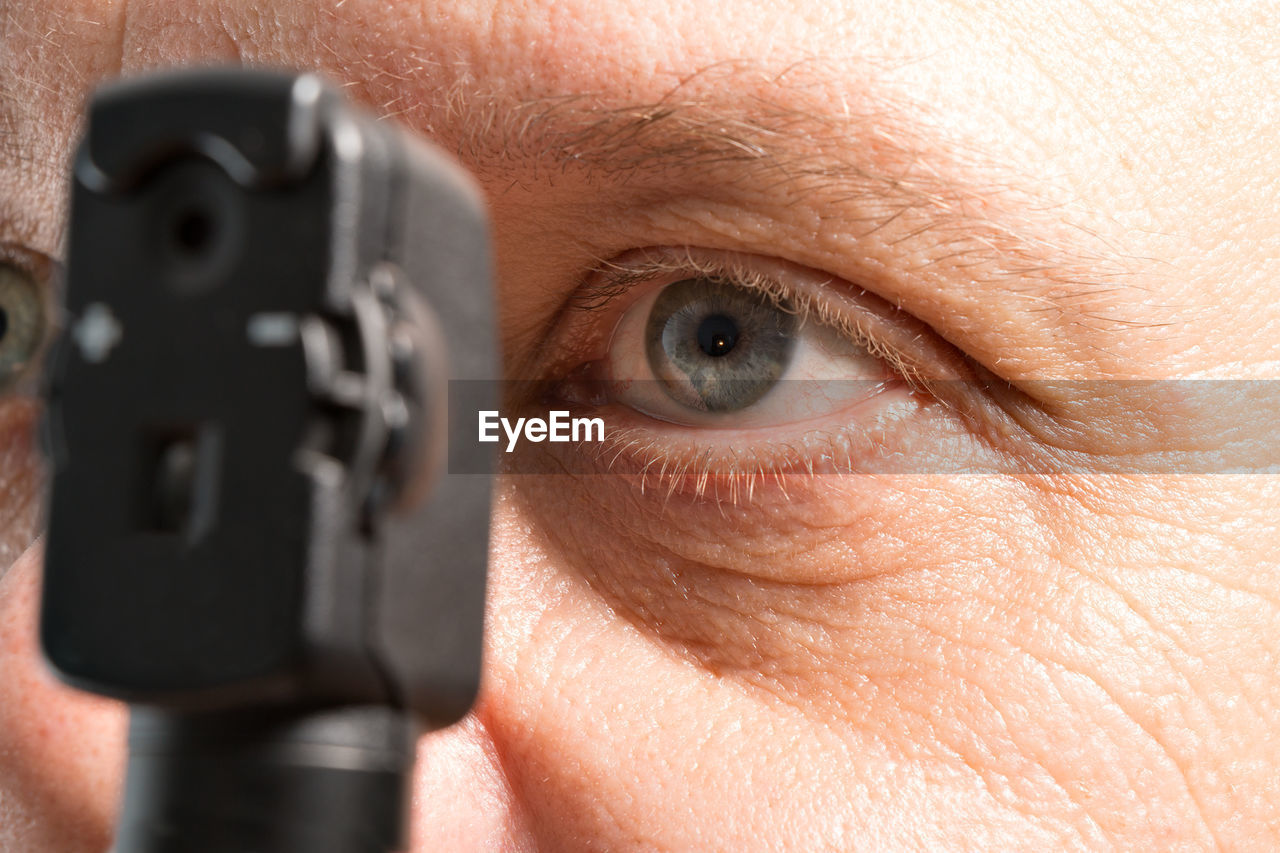 Cropped image of man looking through technology equipment