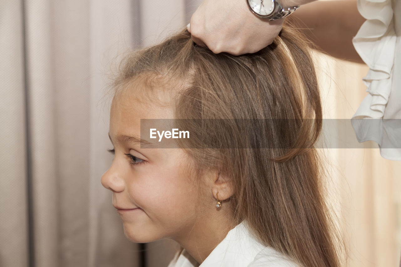 Midsection of mother tying daughter hair