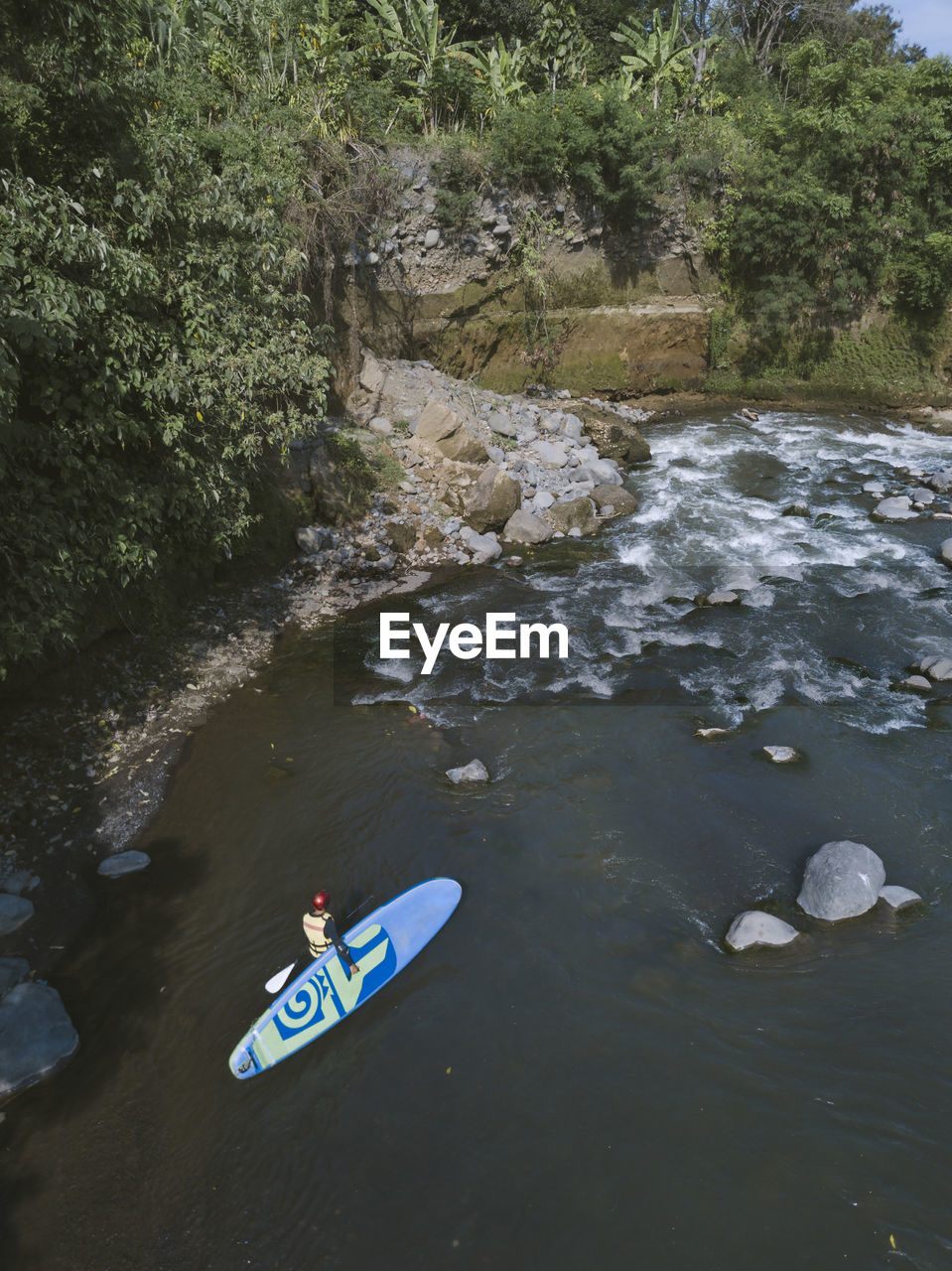 Surfer with sup surfboard at river