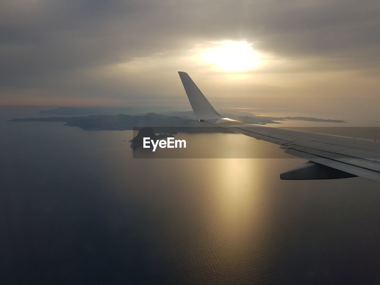 Cropped image of airplane over sea against sky
