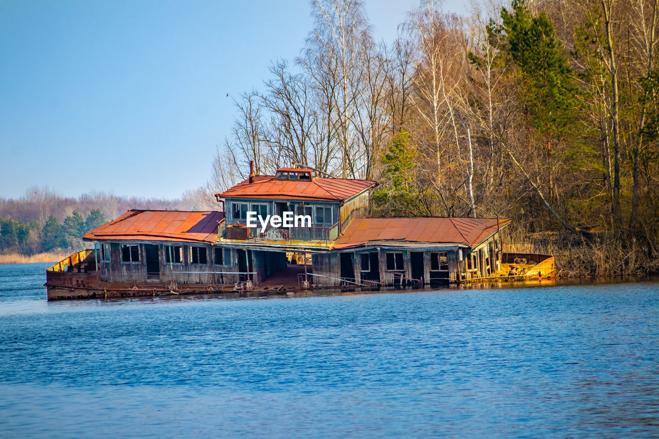 HOUSE BY LAKE AGAINST BUILDINGS