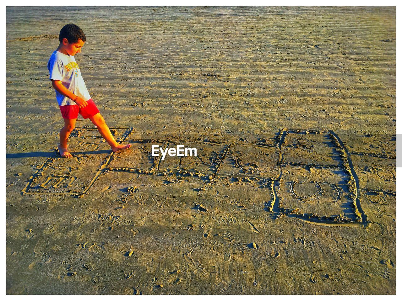 Side view of boy playing on hopscotch