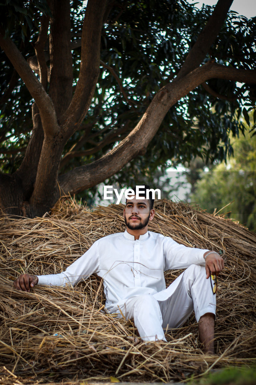 Portrait of young man sitting on field