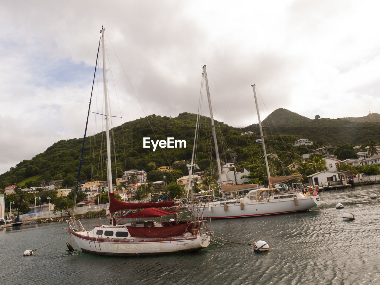 Boats moored at harbor against cloudy sky