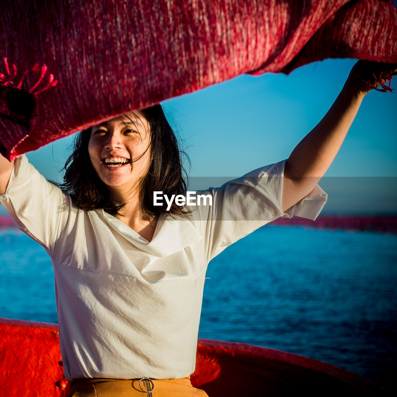Portrait of smiling woman holding scarf on boat