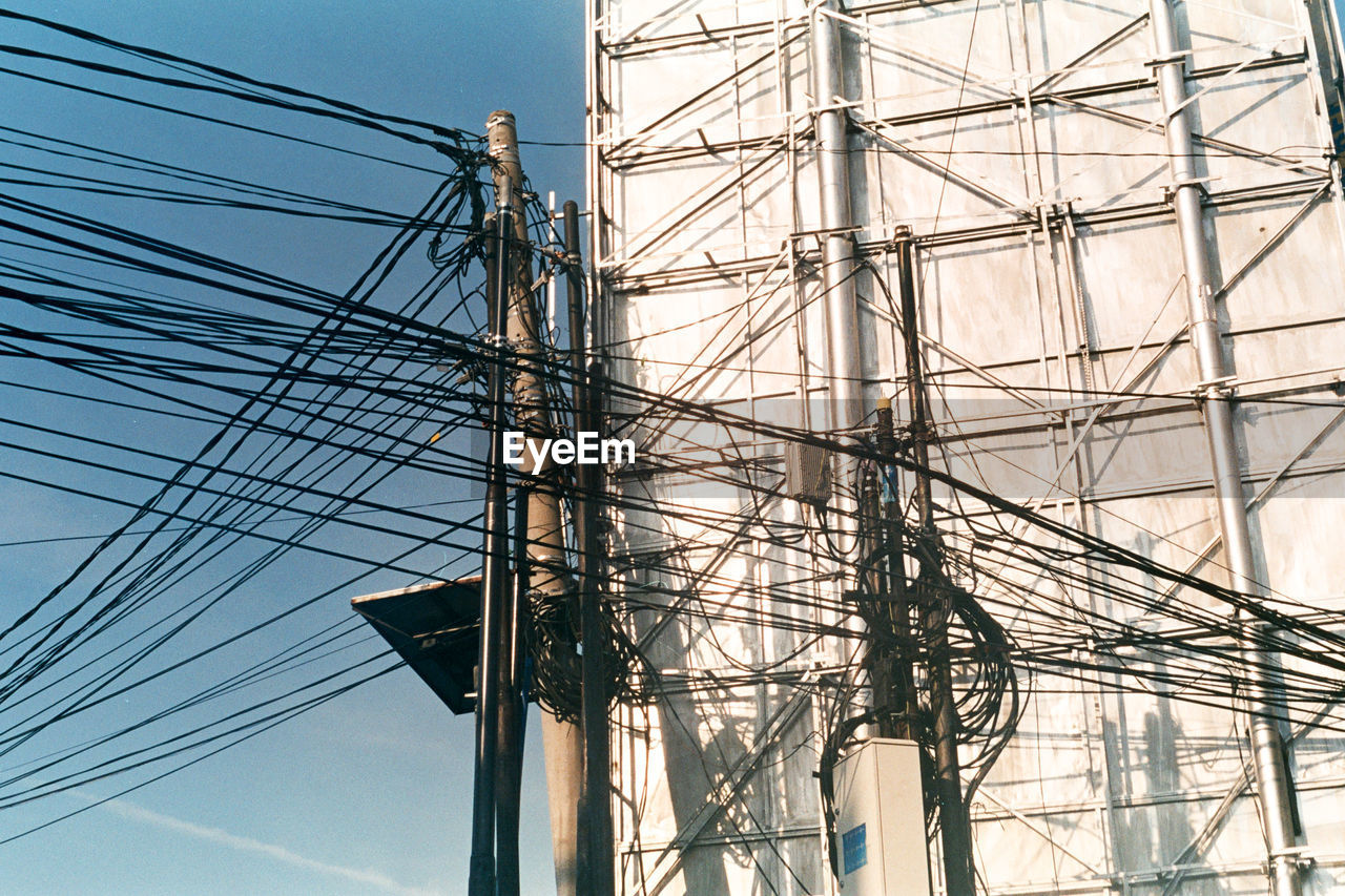 Low angle view of electricity pylon against blue sky