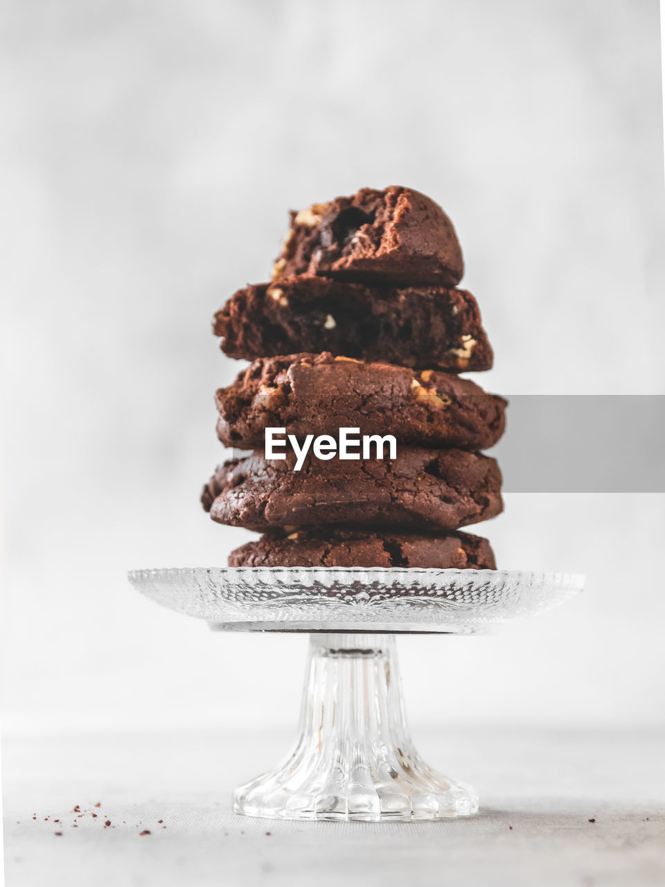 Close-up of stack of chocolate chip cookies on crystal glass stand on table 