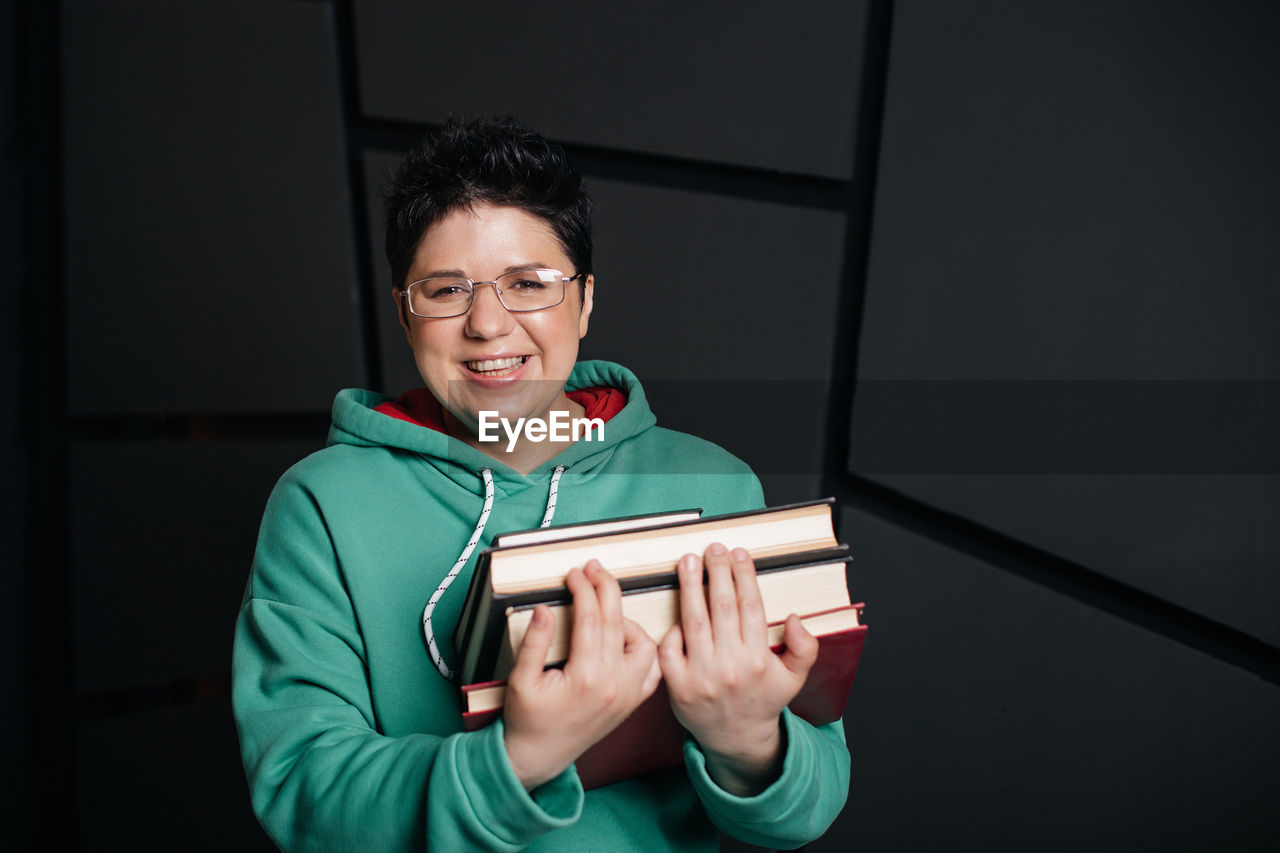 PORTRAIT OF SMILING YOUNG MAN HOLDING SMART PHONE IN BOX