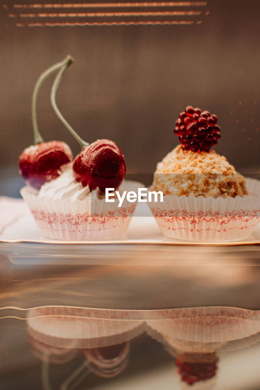 Sweet tiny cakes with fluffy cream and red cherries