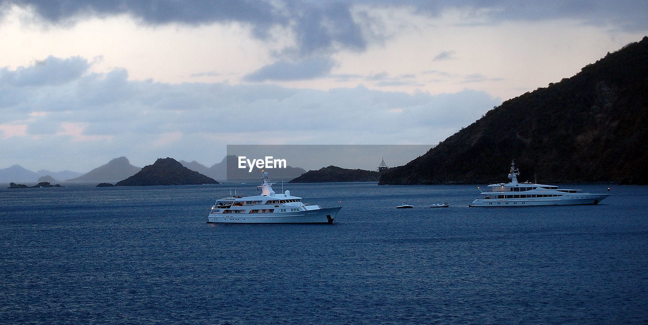 BOATS SAILING IN SEA AGAINST SKY