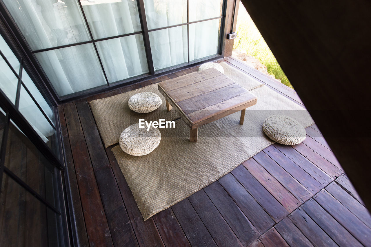 Low table and pillow on mat in wooden floor.