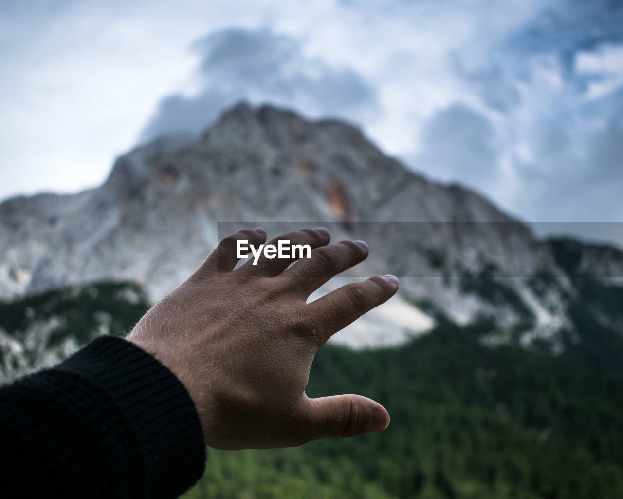 Close-up of human hand against mountain