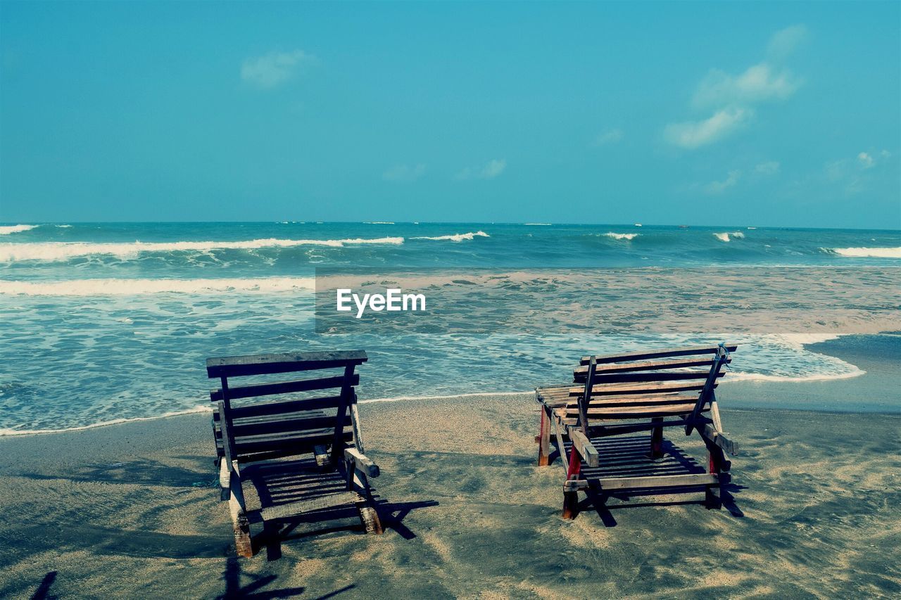 Chairs on beach against sky