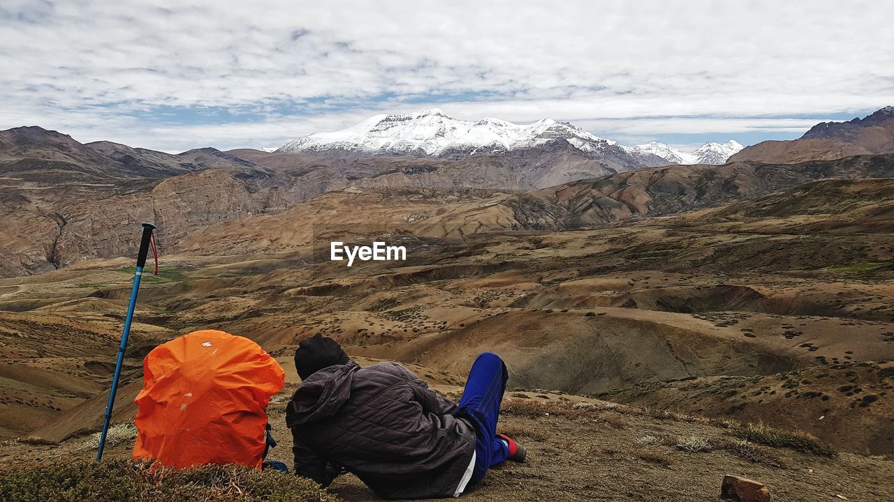 REAR VIEW OF MEN WITH MOUNTAINS IN BACKGROUND