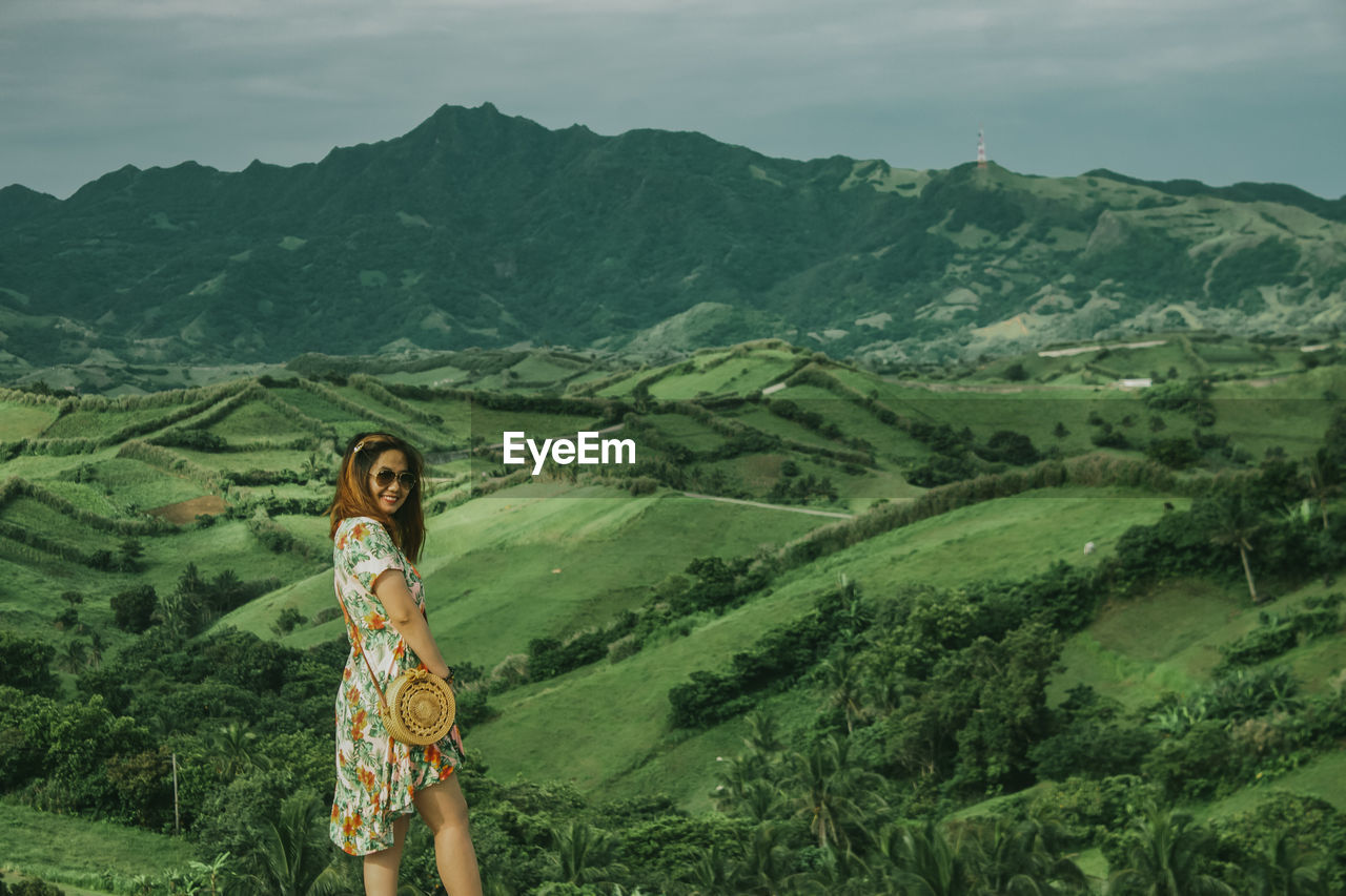 Portrait of woman standing on mountain landscape