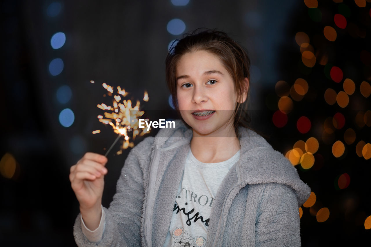 child, portrait, one person, childhood, celebration, christmas, christmas tree, smiling, night, looking at camera, happiness, illuminated, front view, emotion, christmas lights, decoration, men, christmas decoration, holiday, holding, tree, waist up, casual clothing, cheerful, event, standing, nature, headshot, focus on foreground, fun, winter, lifestyles, indoors, person, teenager, positive emotion