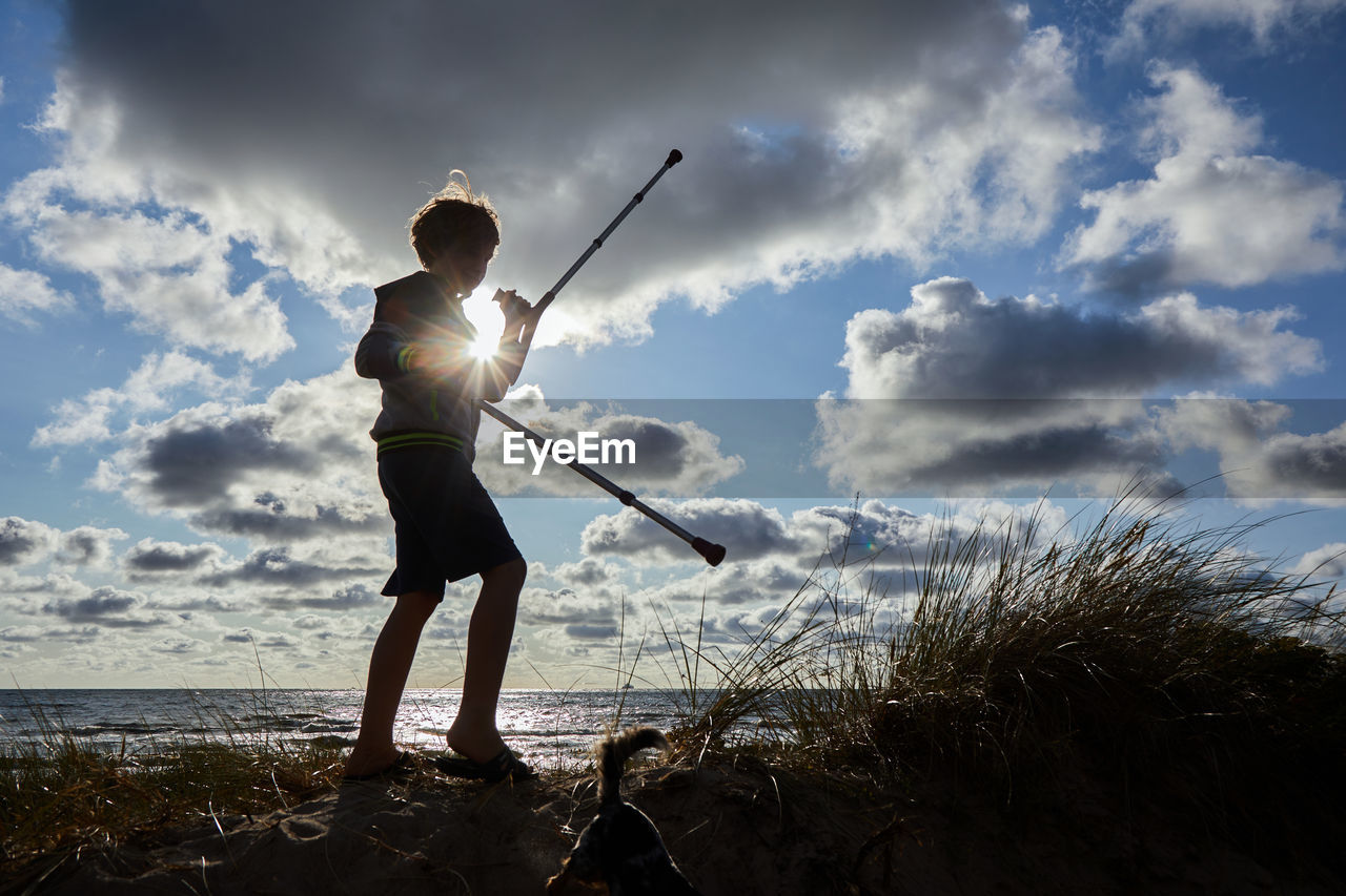 MAN STANDING ON BEACH AGAINST SKY