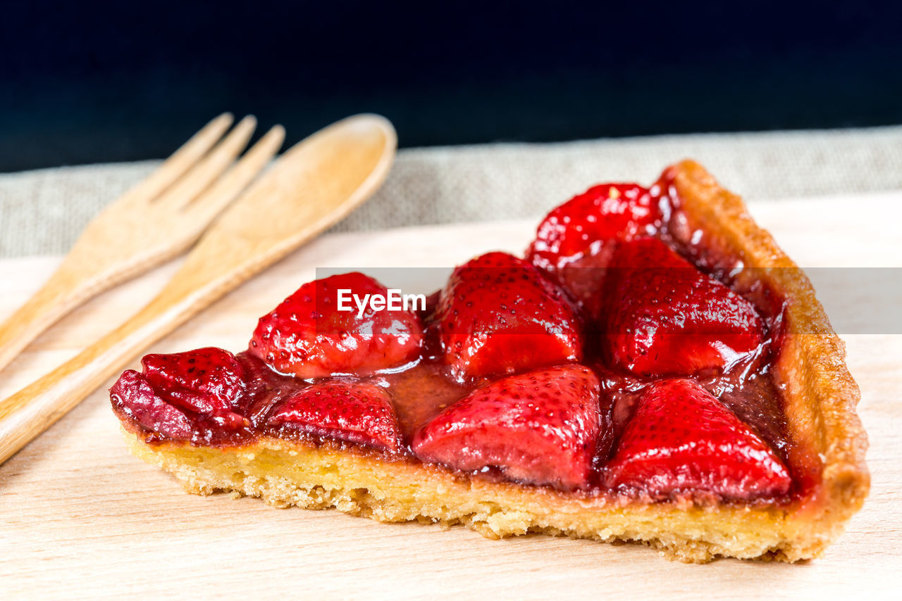 High angle view of strawberry tart slice on cutting board