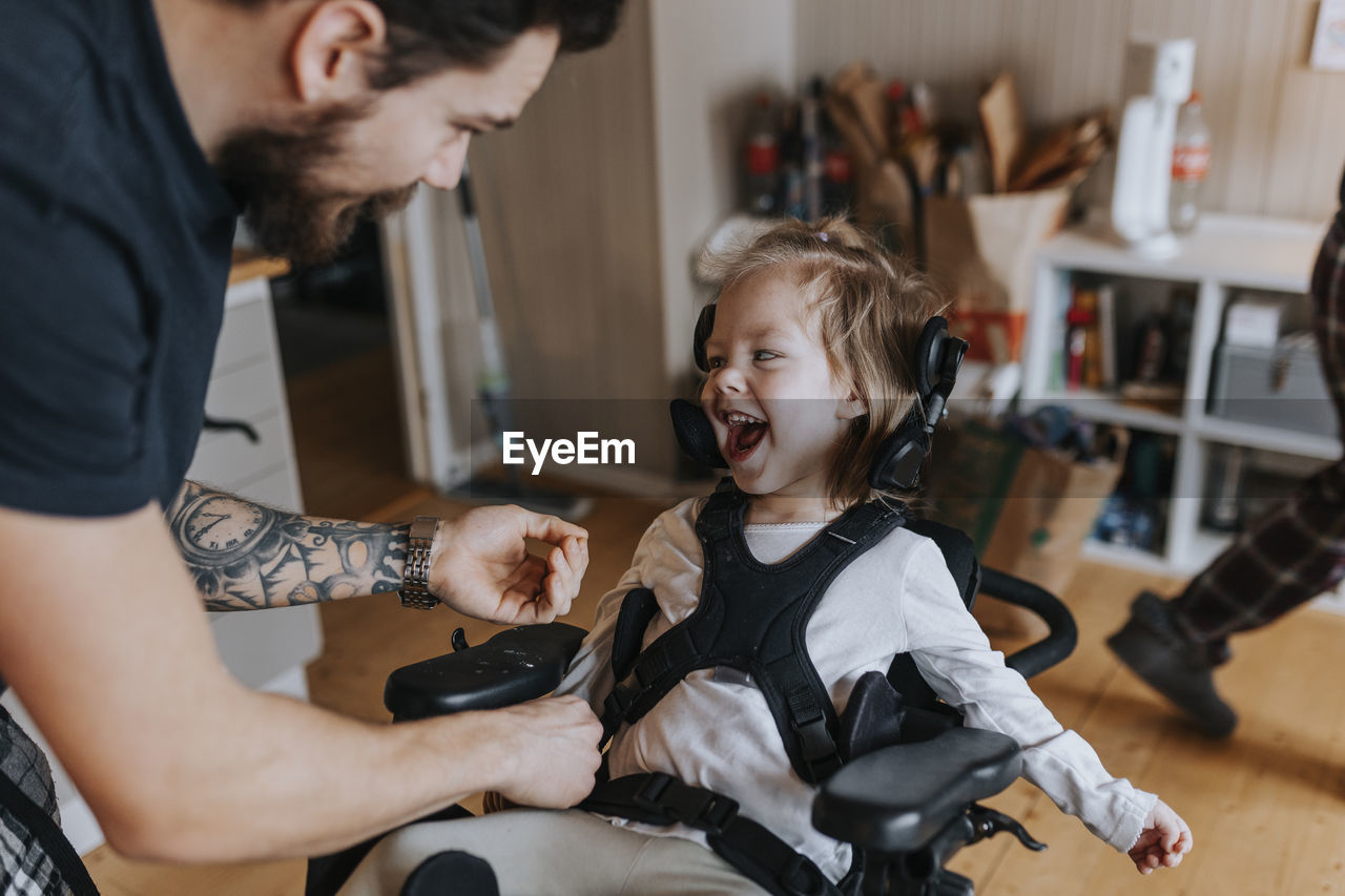 Father taking care of happy disabled child in wheelchair