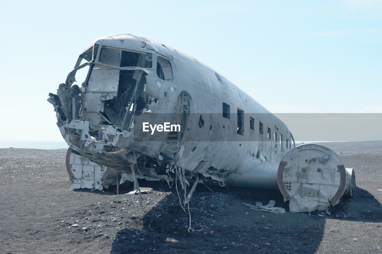 ABANDONED AIRPLANE ON SAND AGAINST CLEAR SKY