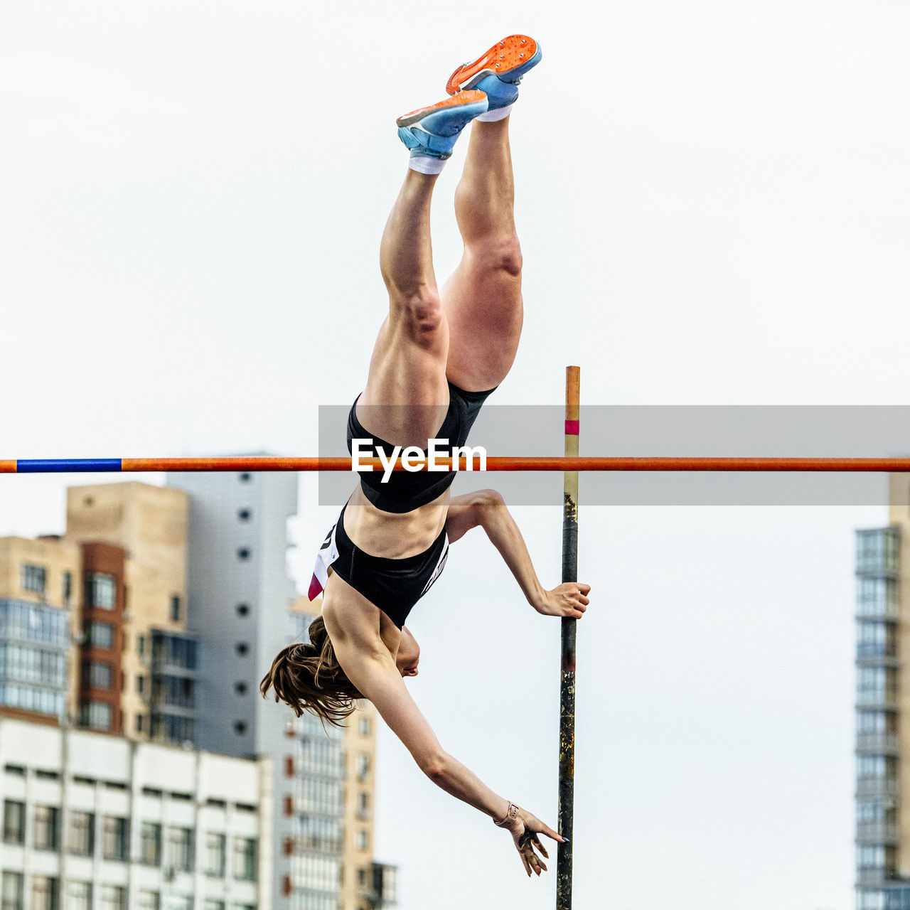 low angle view of young woman standing on railing against clear sky