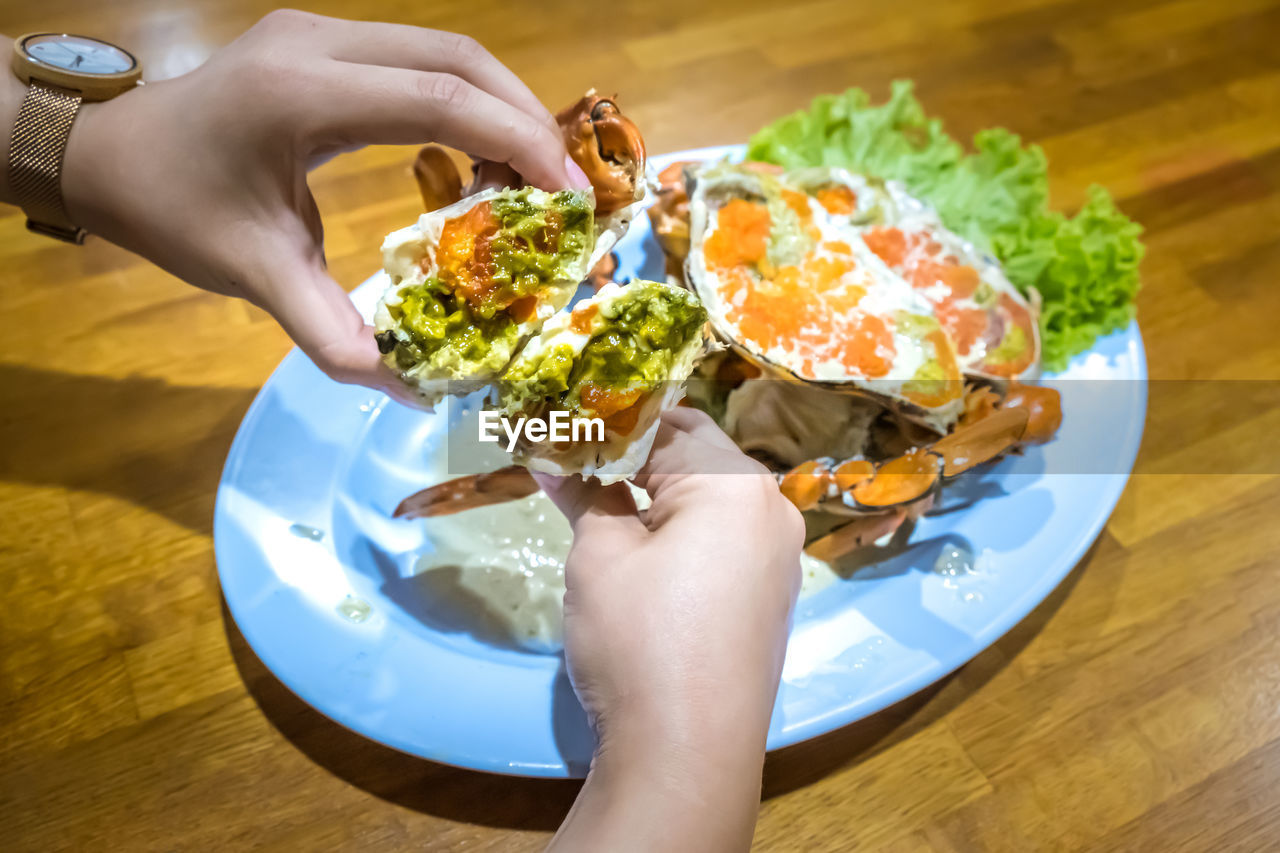 High angle view of hand holding food in plate on table