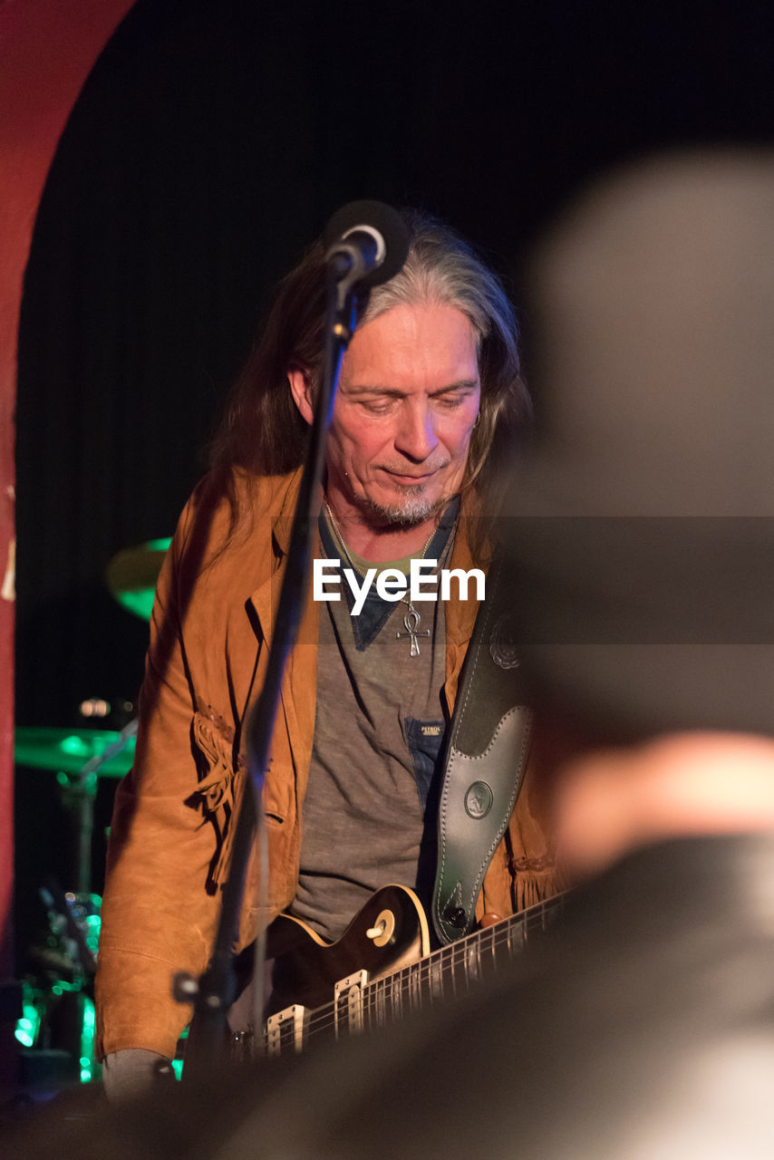 Man playing guitar while standing on stage