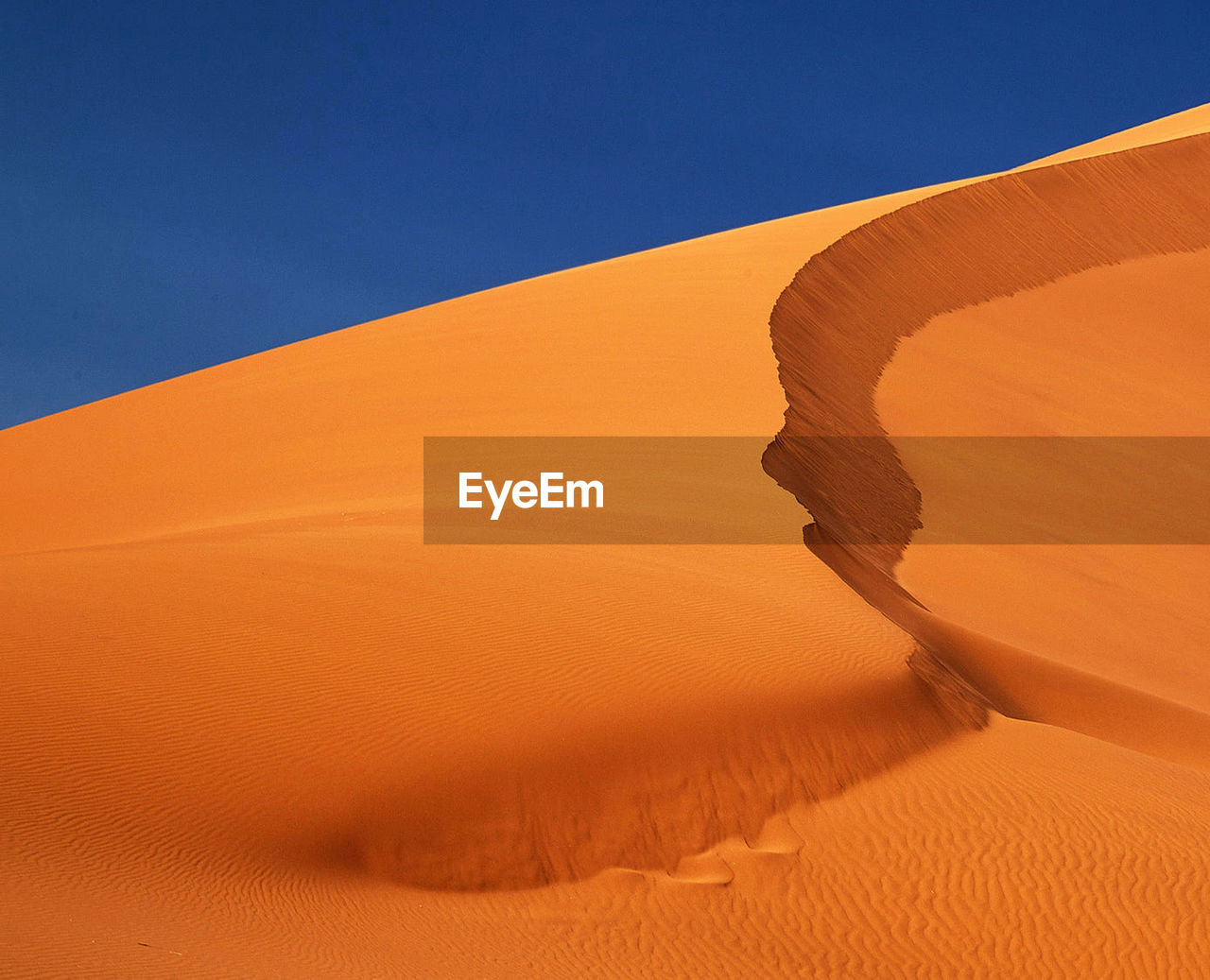 Sand dunes in desert against clear sky