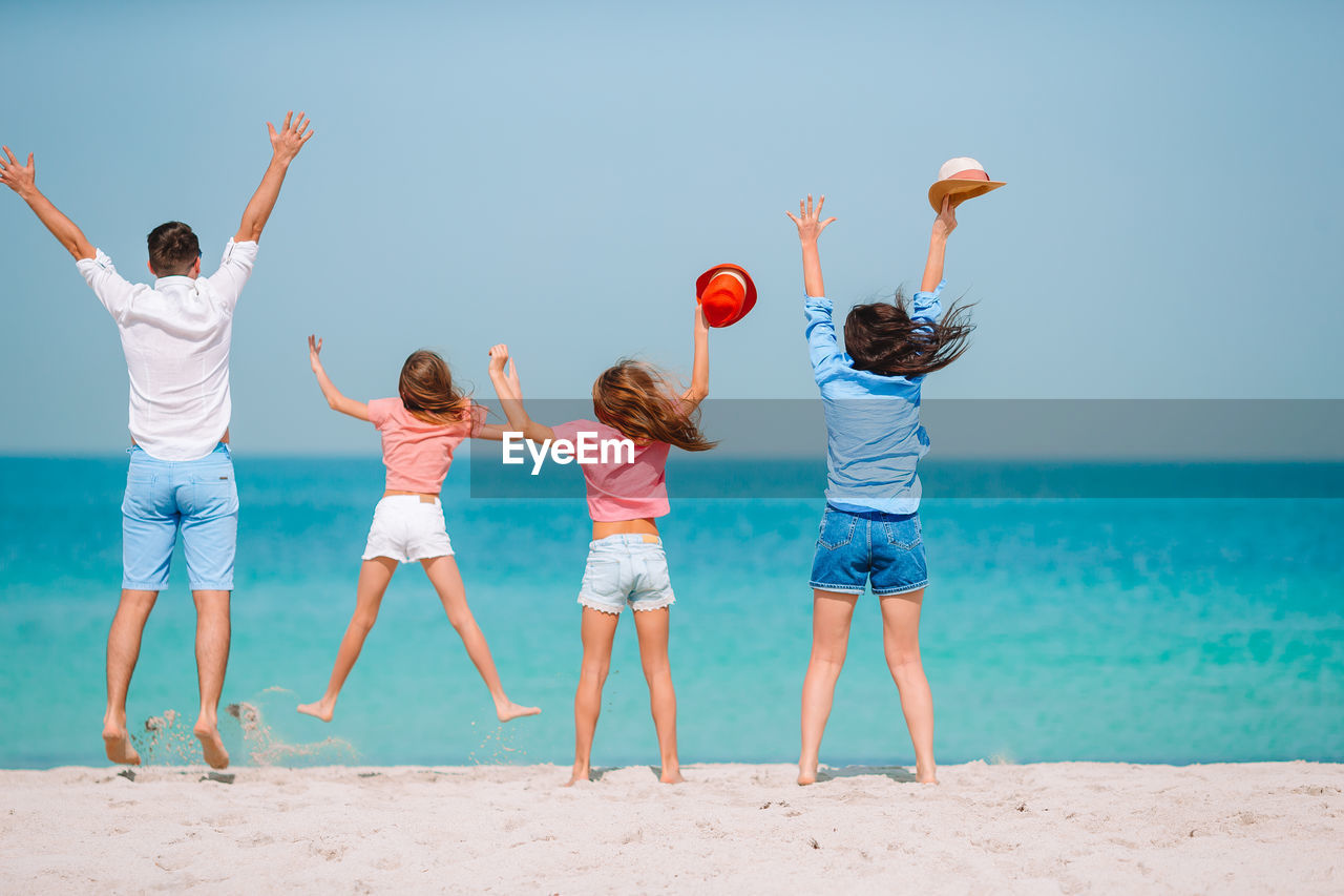 Rear view of family jumping at beach