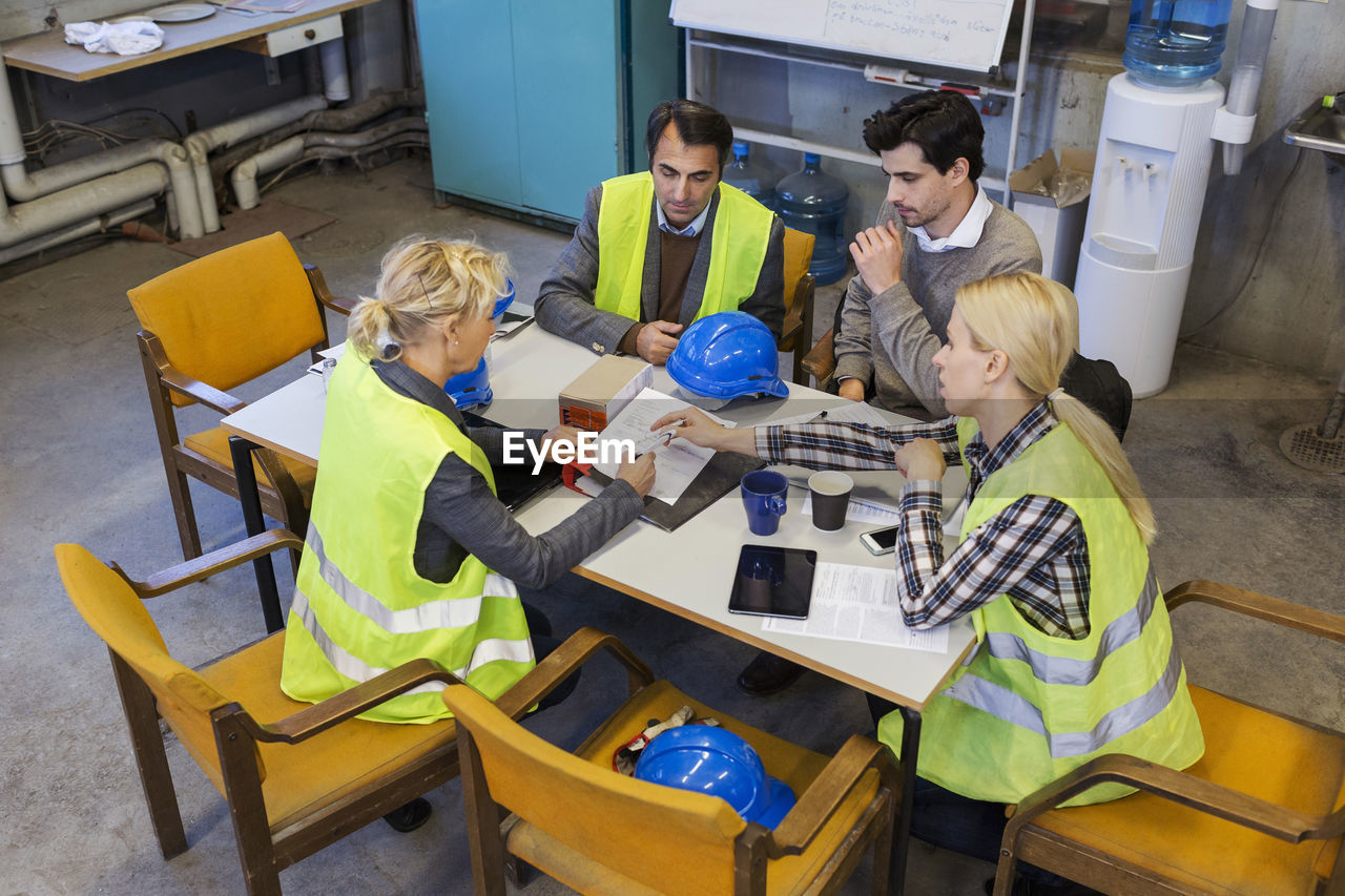 Manual workers planning at table in factory