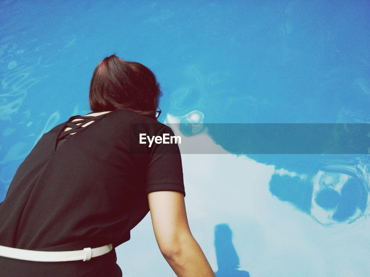 Rear view of woman standing at swimming pool