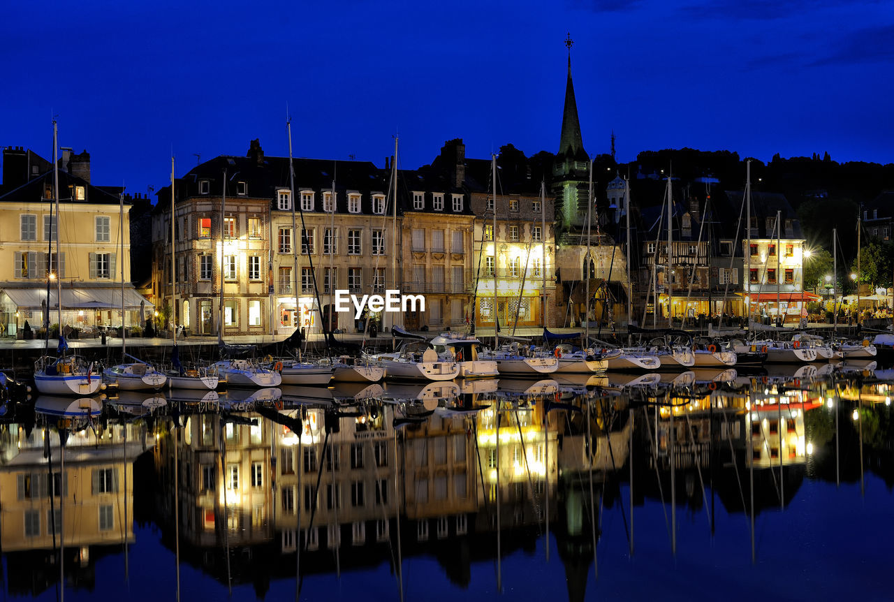 Sailboats moored on illuminated buildings in city at night