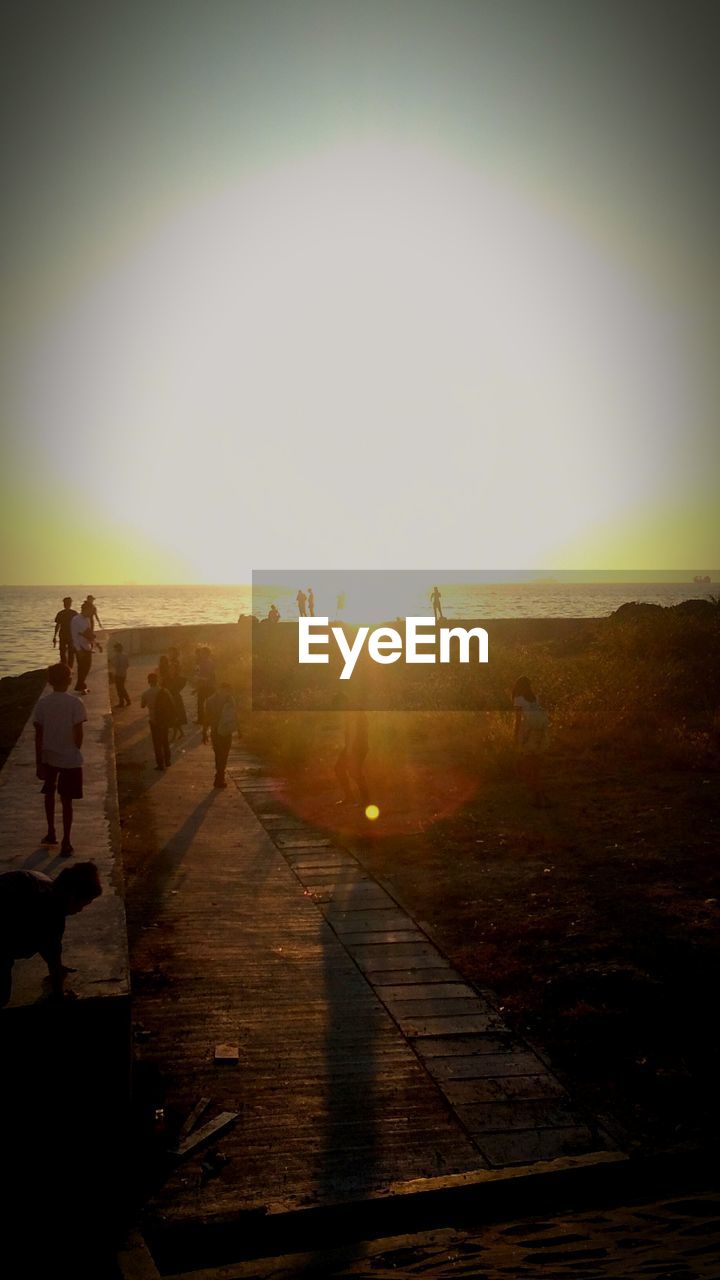 GROUP OF PEOPLE WALKING ON FOOTPATH AGAINST SKY