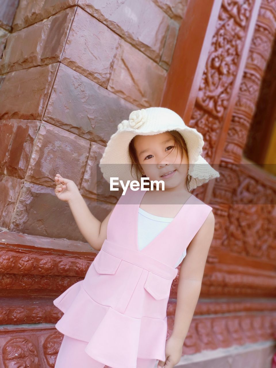 Portrait of smiling girl standing against built structure