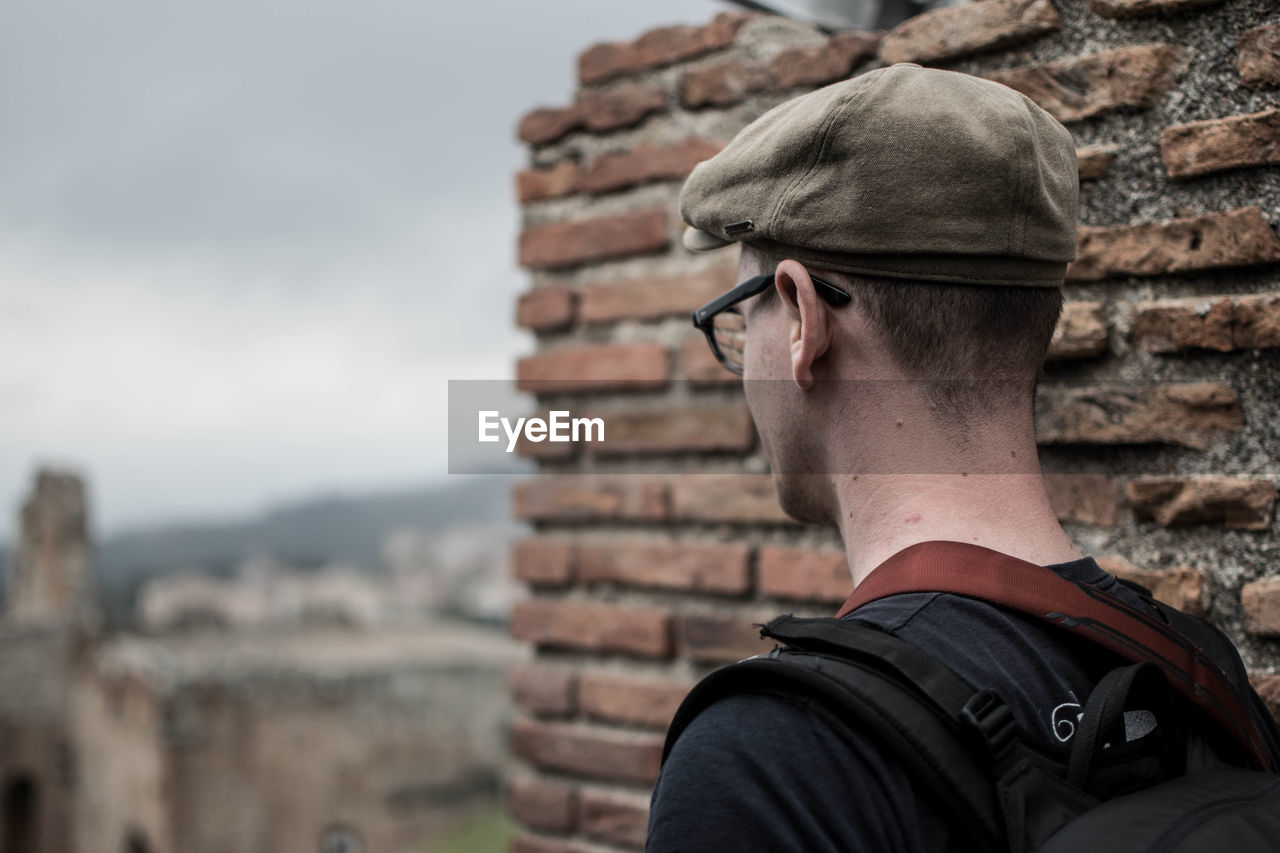 FULL LENGTH REAR VIEW OF MAN WEARING MASK AGAINST WALL