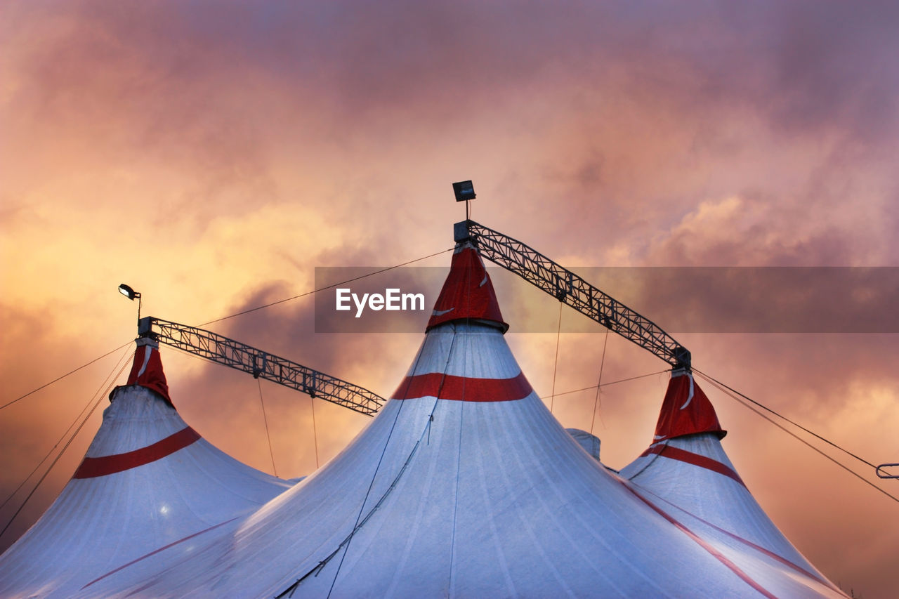 Circus tent in a dramatic sunset sky colorful orange blue with lights
