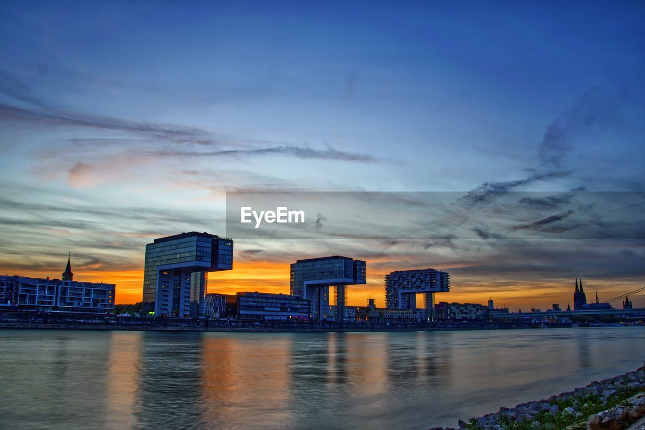RIVER AND BUILDINGS AGAINST SKY AT SUNSET