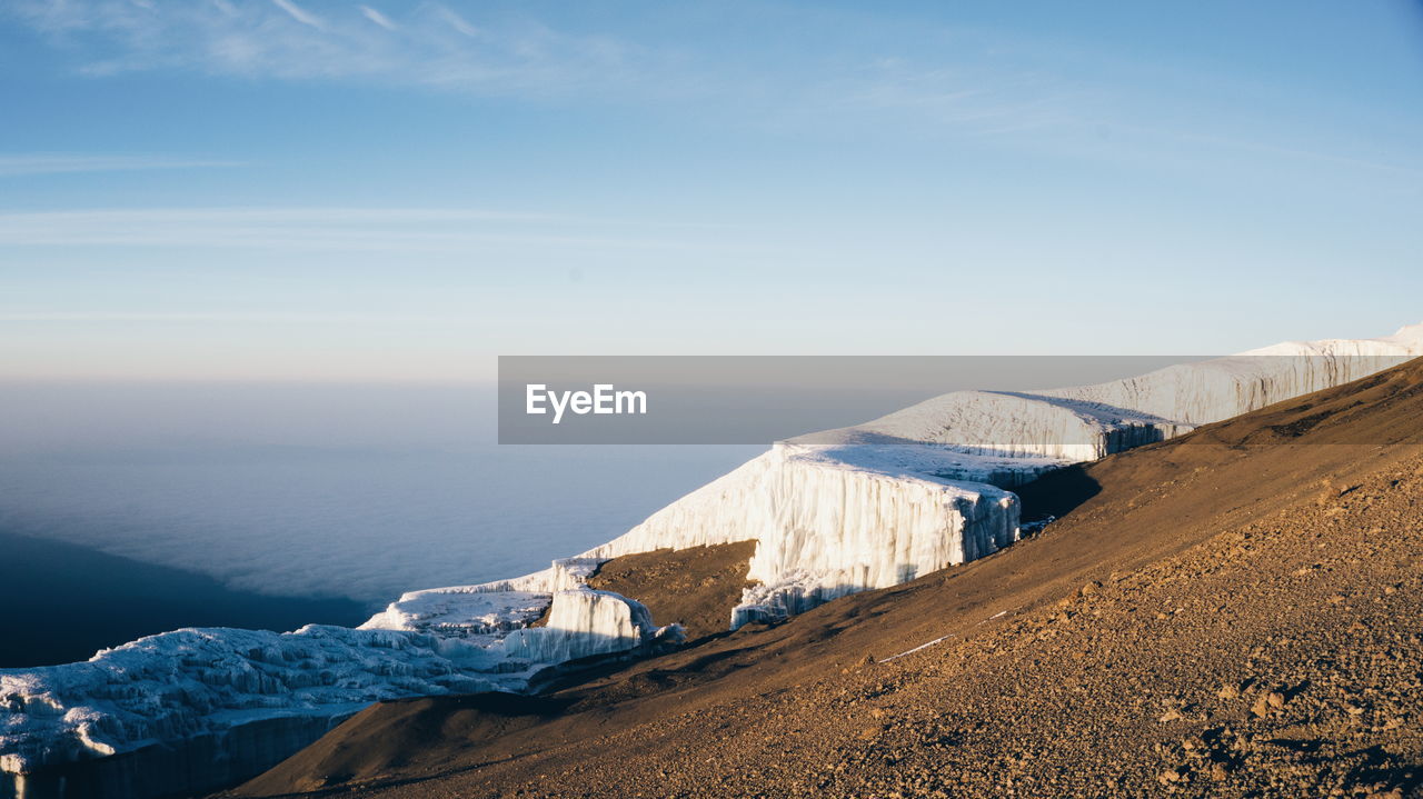 Snow on mountain by sea against sky