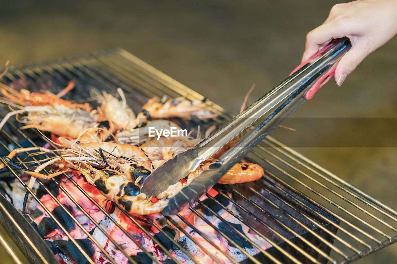 Close-up of person preparing food on barbecue grill